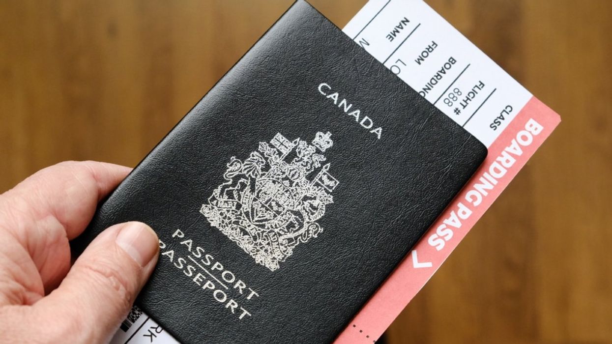 A person holding a Canadian passport with a boarding pass tucked inside of it.