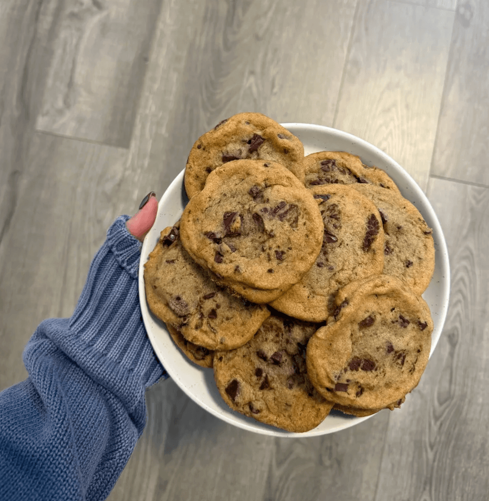 A person holding a plate of cookies.