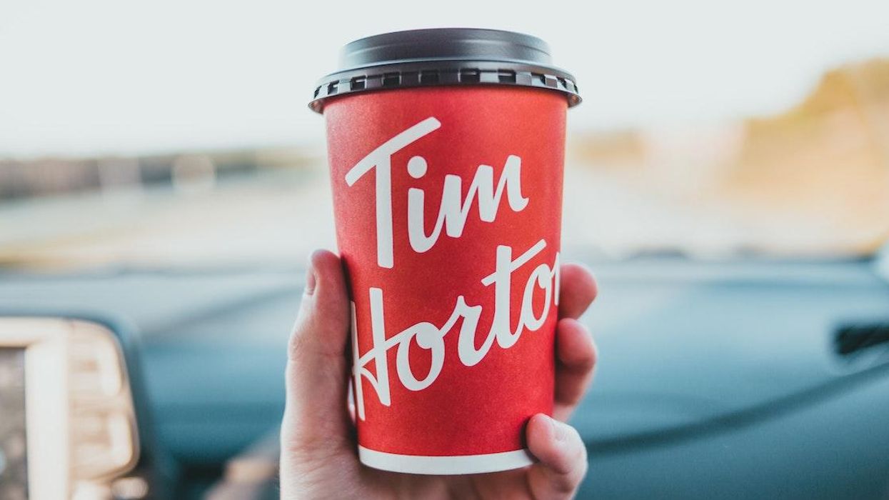 A person holding a Tim Hortons coffee cup.
