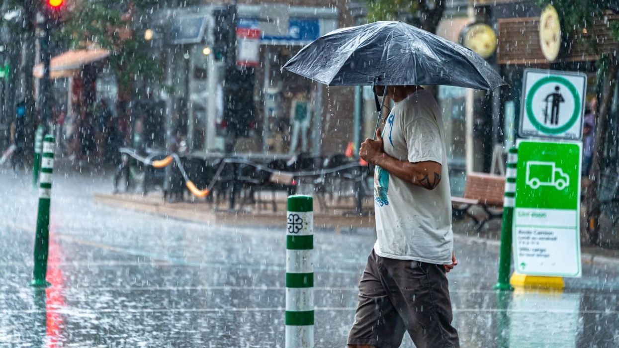 A person holding an umbrella in Le Plateau-Mont-Royal during a rainstorm.