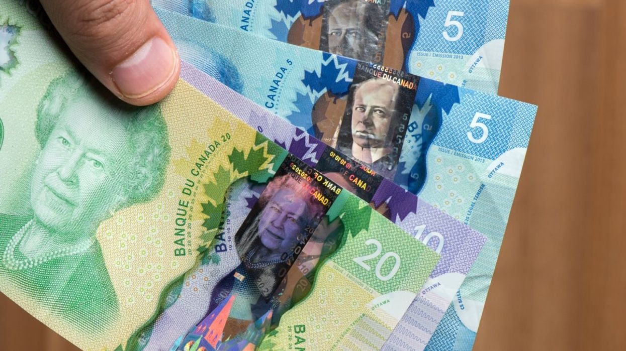 A person holding two Canadian five dollar bills, one ten dollar bill and one twenty dollar bill.