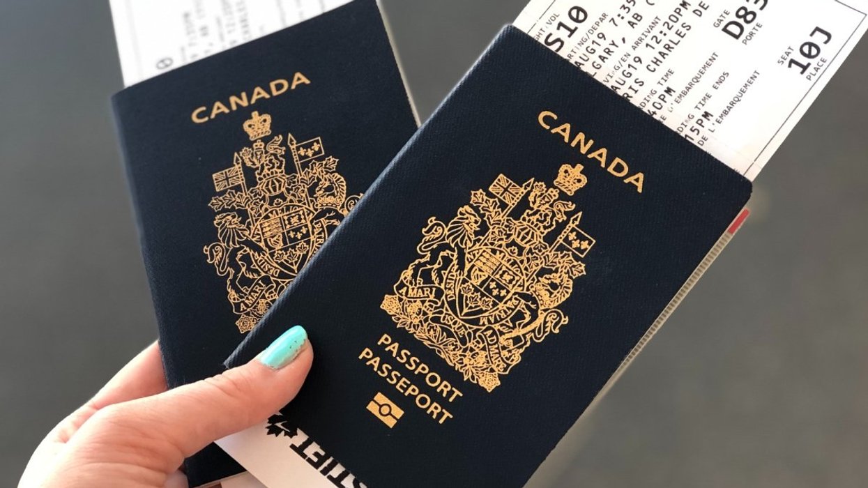 A person holding two Canadian passports with boarding passes tucked inside.