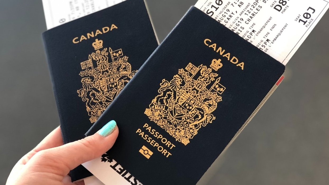 A person holding two Canadian passports with boarding passes tucked inside.