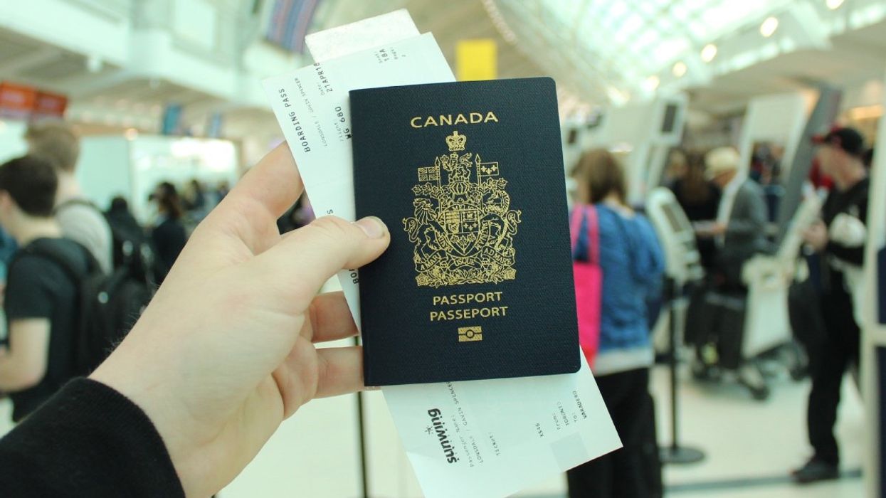A person holding up a Canadian passport in an airport.