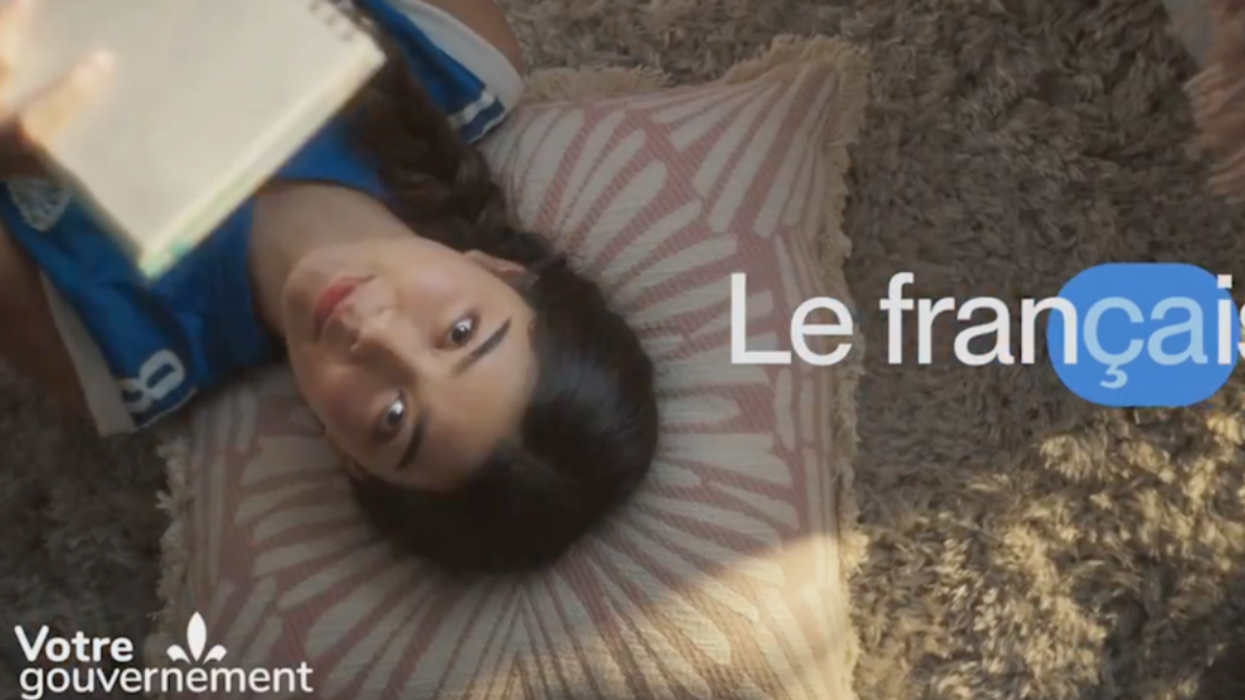 A person lying down, face up, holding a note pad with the words "Le Francais" on screen.