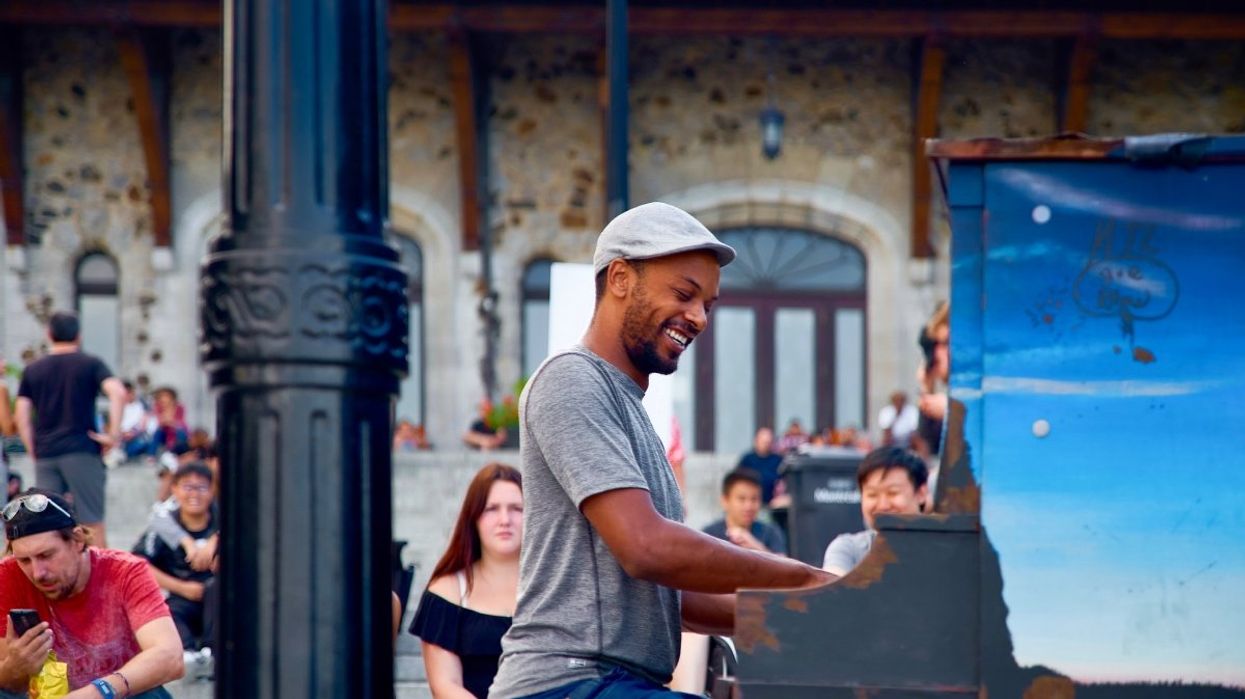 A person playing piano at Montreal's Mont-Royal chalet while people watch in the distance.