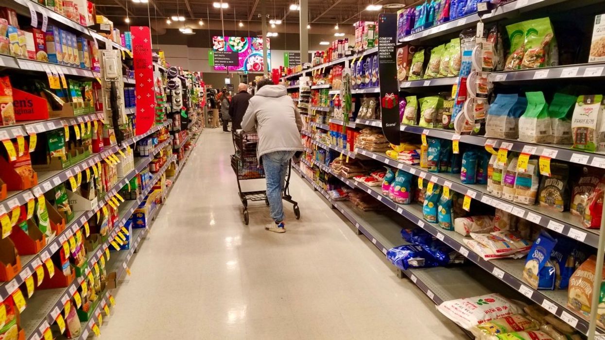 A person pushing a shopping cart through a grocery aisle at a Canadian supermarket.