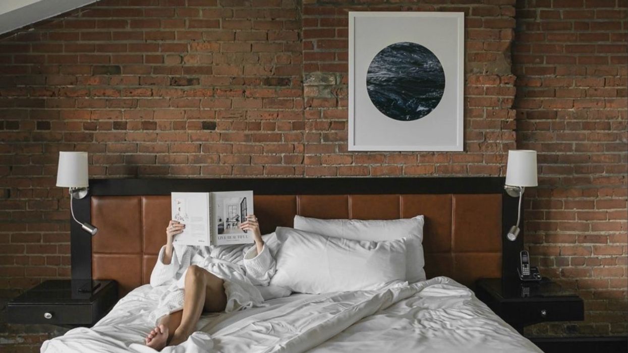 A person reading a book in bed at the Hotel Place D'Armes in Montreal, Quebec.