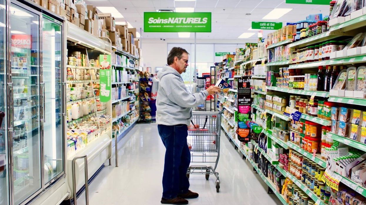 A person reading the product information of a grocery item in the aisle of a Canadian supermarket.
