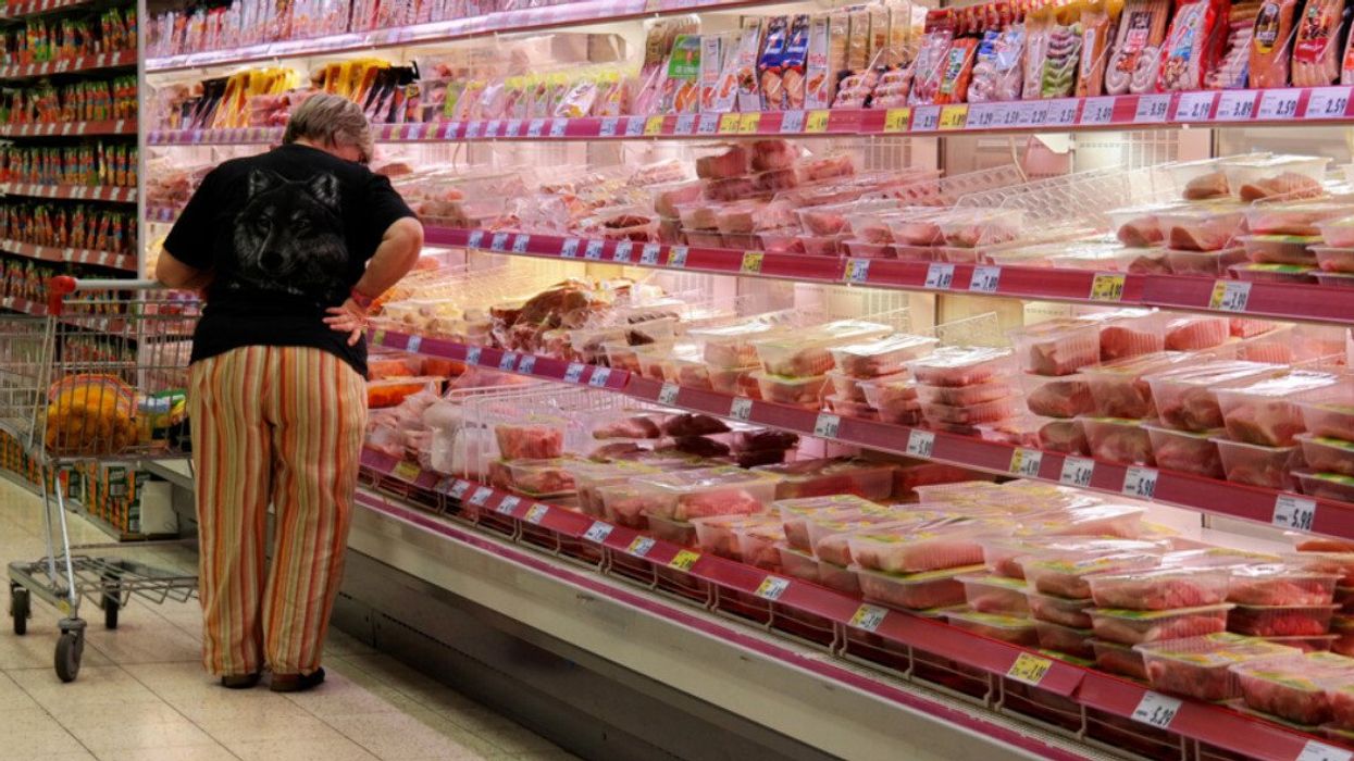 A person shopping for meat in a supermarket.