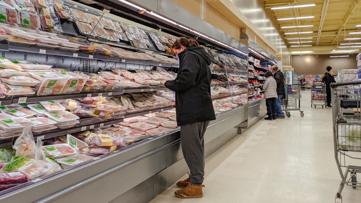 A person standing in the meat and produce section of a grocery store in Canada.