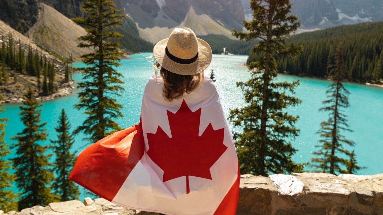 A person wearing a Canadian flag overlooking Lake Moraine in Banff National Park.
