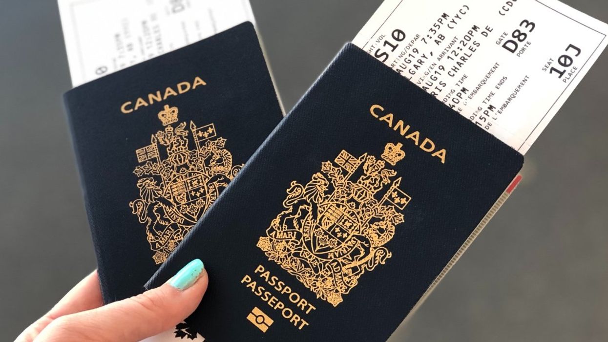 A person with blue nail polish holding two passports in an airport.