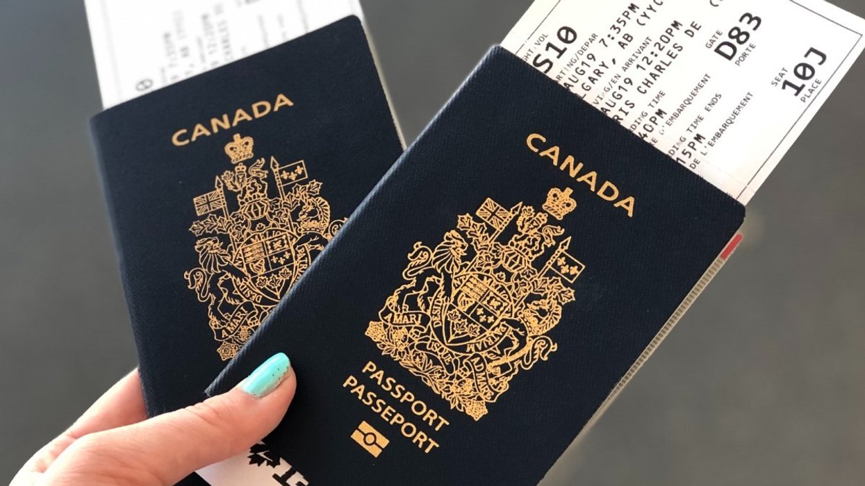 A person with blue nail polish holding two passports in an airport.