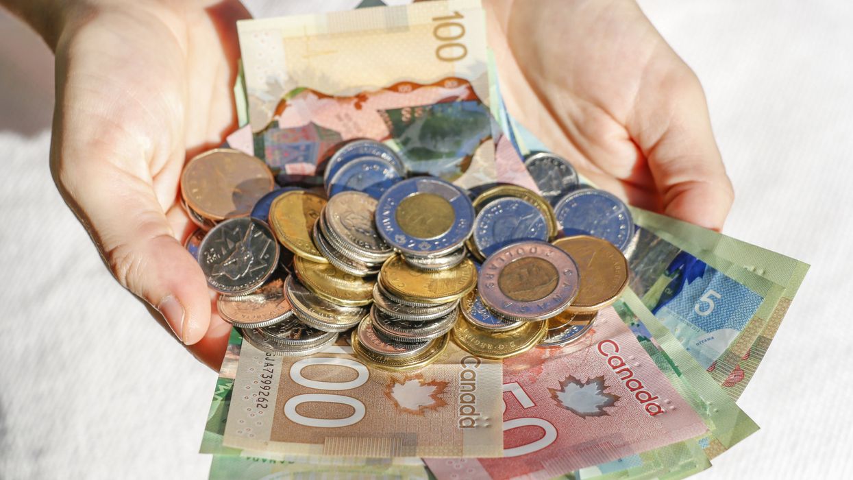 A pile of Canadian bills and coins in outstretched hands (illustrative).