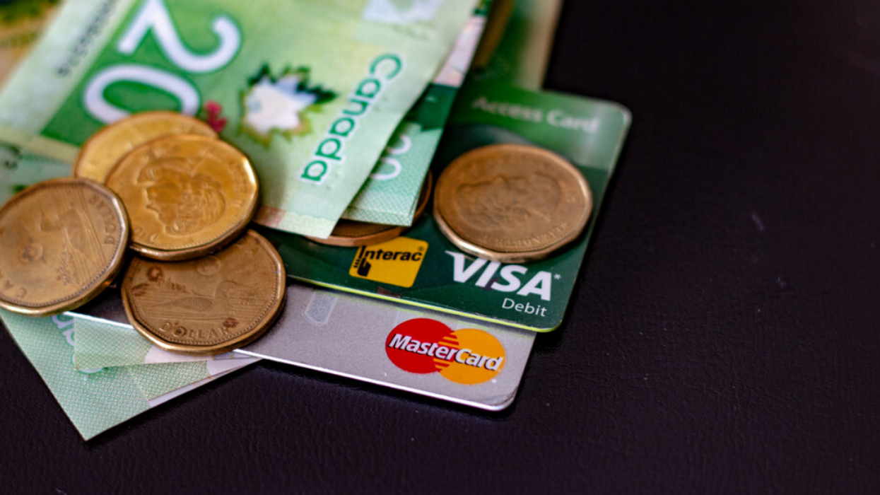 A pile of Canadian money and cards on a black table.
