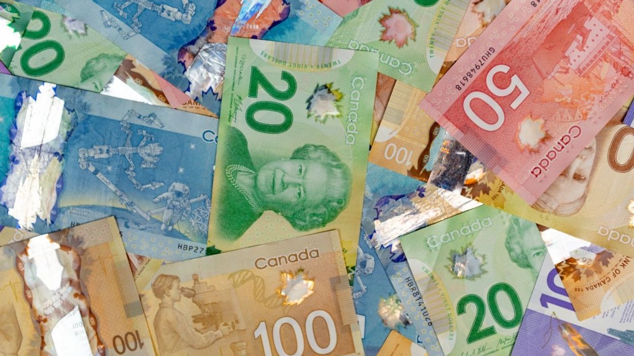 A pile of Canadian money including various $100, $50, $20, $10 and $5 banknotes.