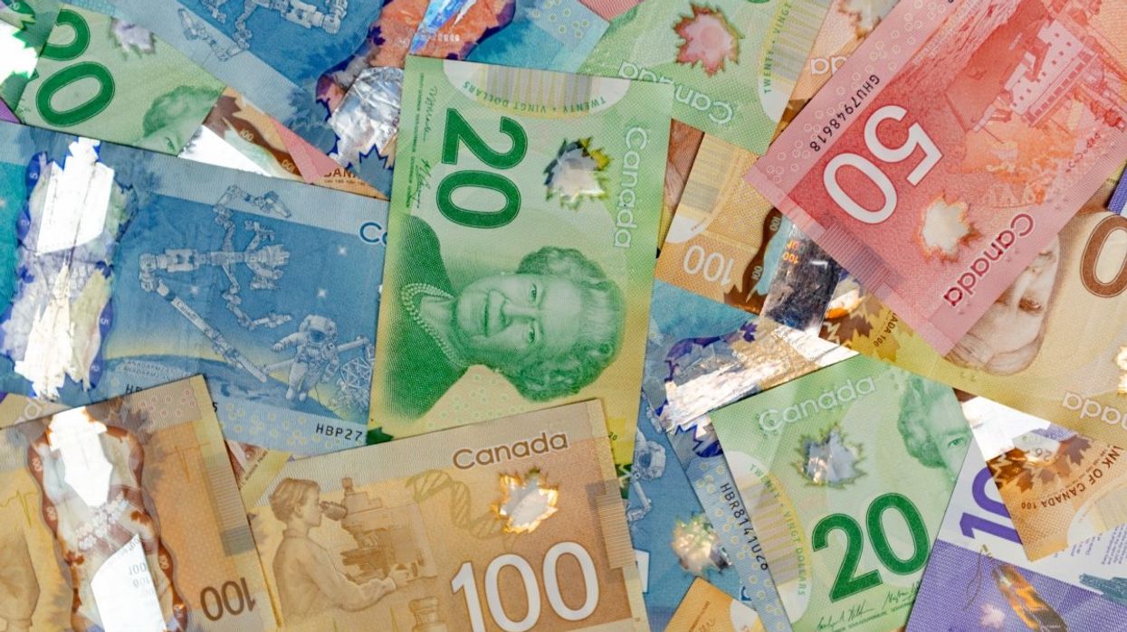 A pile of Canadian money including various $100, $50, $20, $10 and $5 banknotes.
