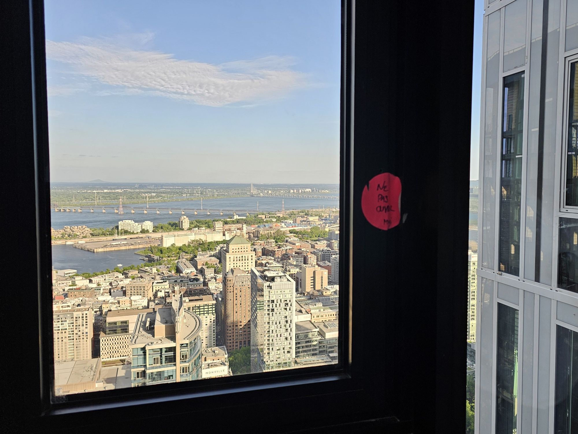 A pink sticker on a penthouse window reads, "Ne pas ouvrir."