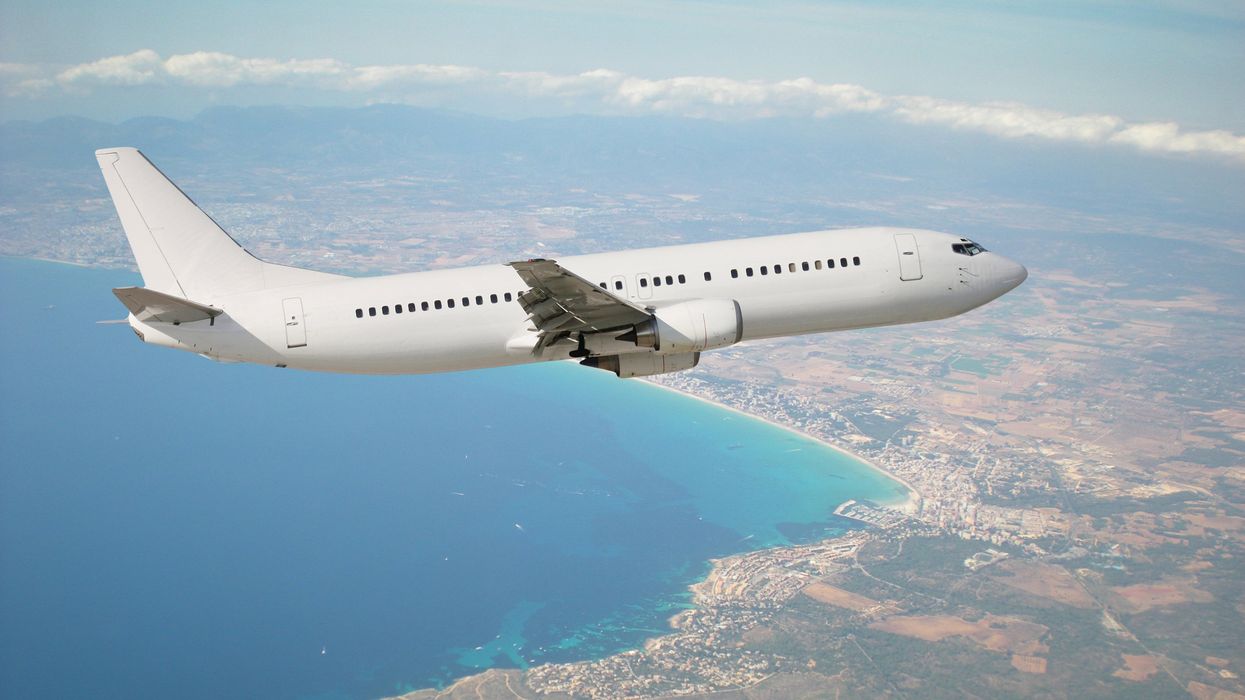A plane flies over water and land.