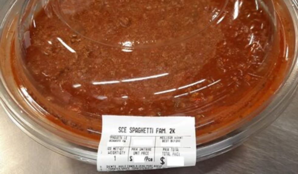 A plastic container filled with red tomato sauce and sealed together with an IGA-branded grocery sticker.