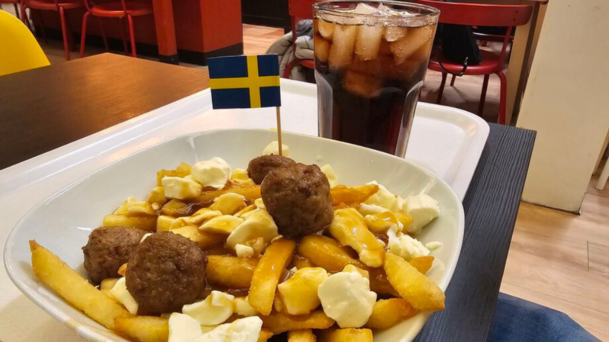A plate of poutine on a tray with a Swedish flag toothpick on a meatball at IKEA in Montreal.
