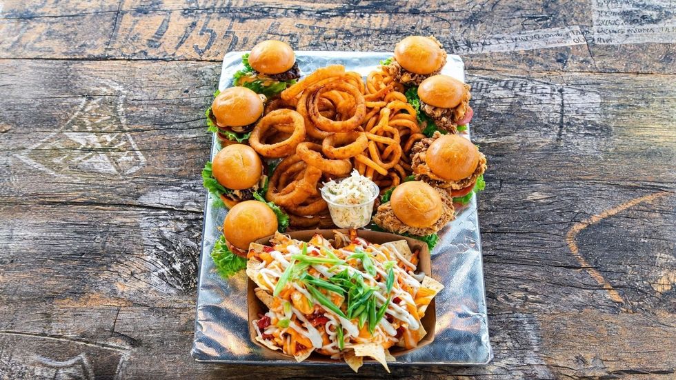 A platter of sliders, onion rings, coleslaw, and nachos from B12 Burger.