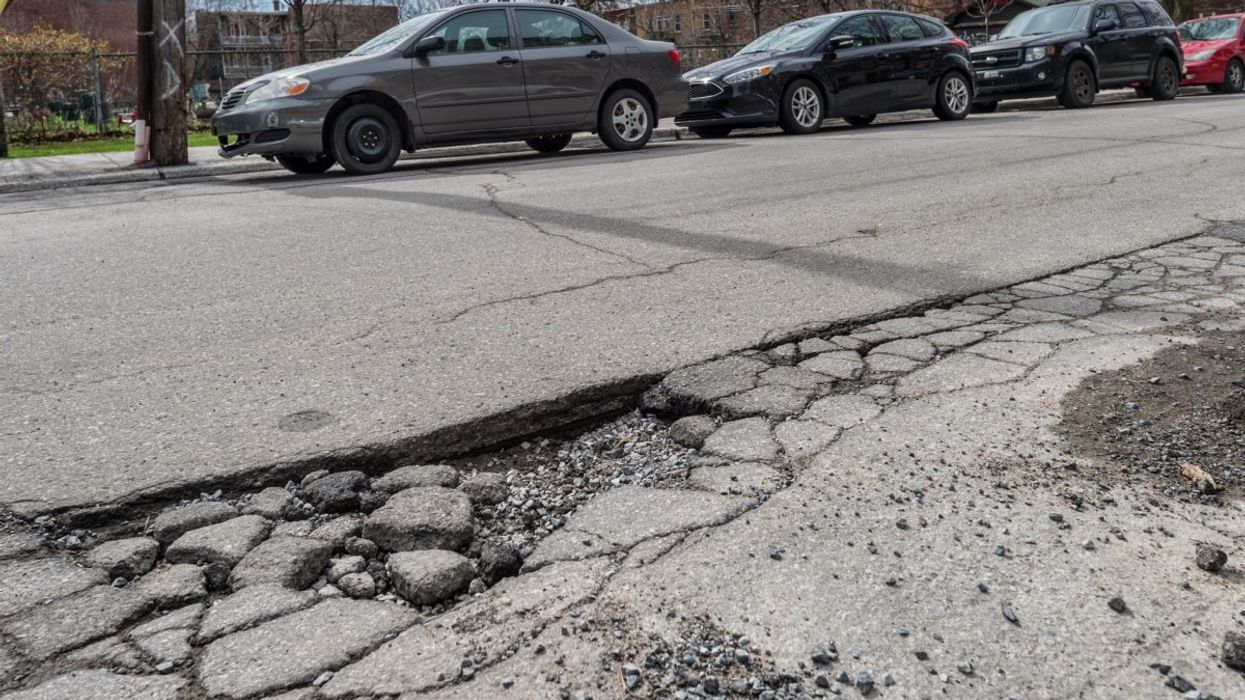A pothole in a road in Montreal with various cars parked on the opposite side of the street.