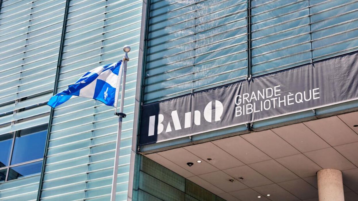 A Quebec flag flies in front of the entrance to the BAnQ Grande Bibliothèque.