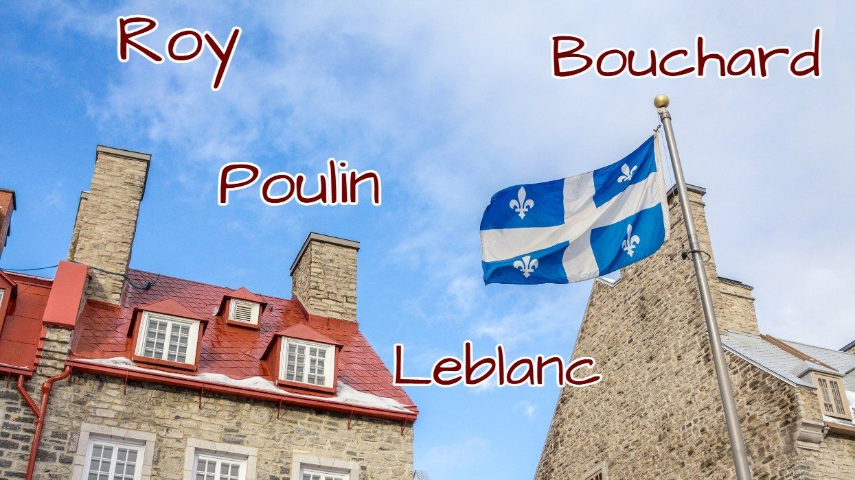 A Quebec flag waves atop a historic building.