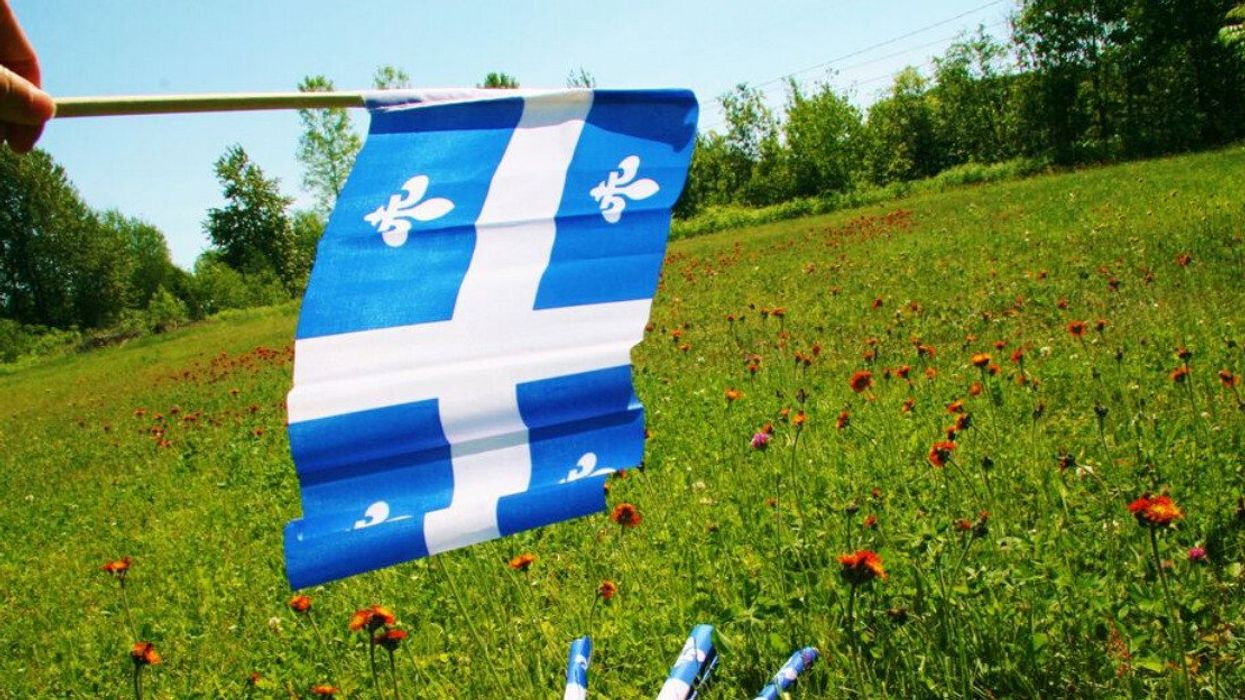 A Quebec flag waves in the grass.