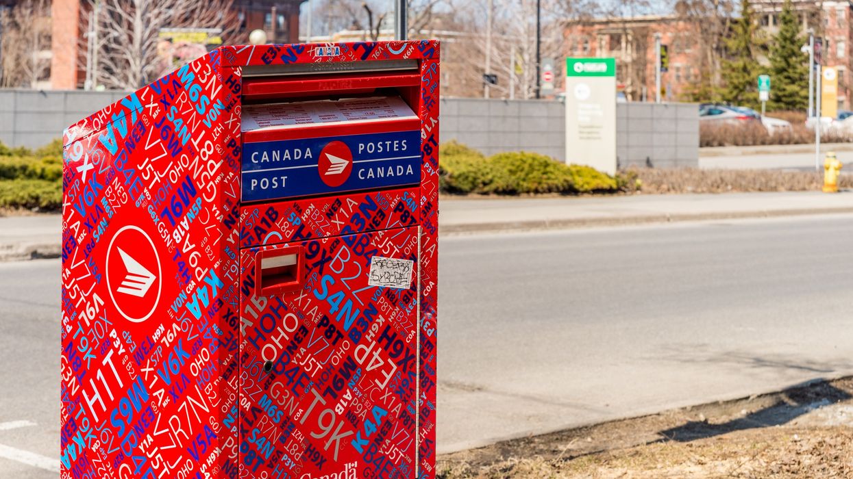 A red Canada Post outgoing mailbox in a residential area.