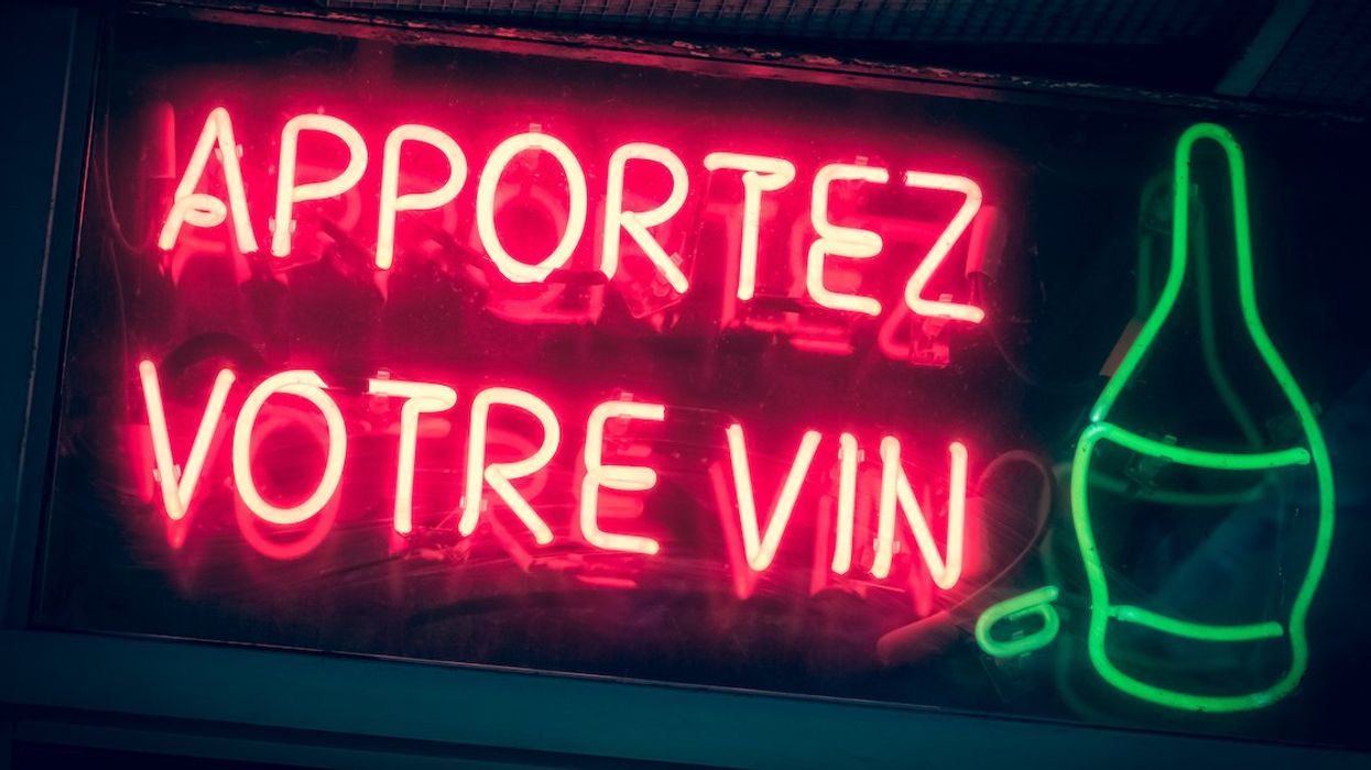 A red neon sign reading, "Apportez votre vin."