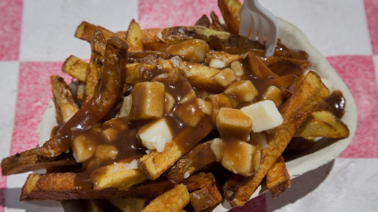 A serving of poutine in a to-go box.