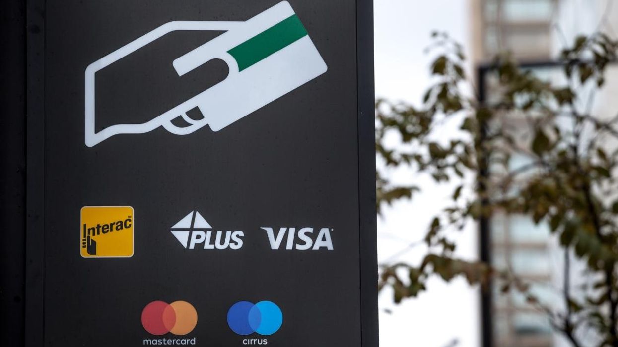 A sign on an ATM with the logos indicating the credit and debit pay cards accepted, that include Visa, Interac and Cirrus,.