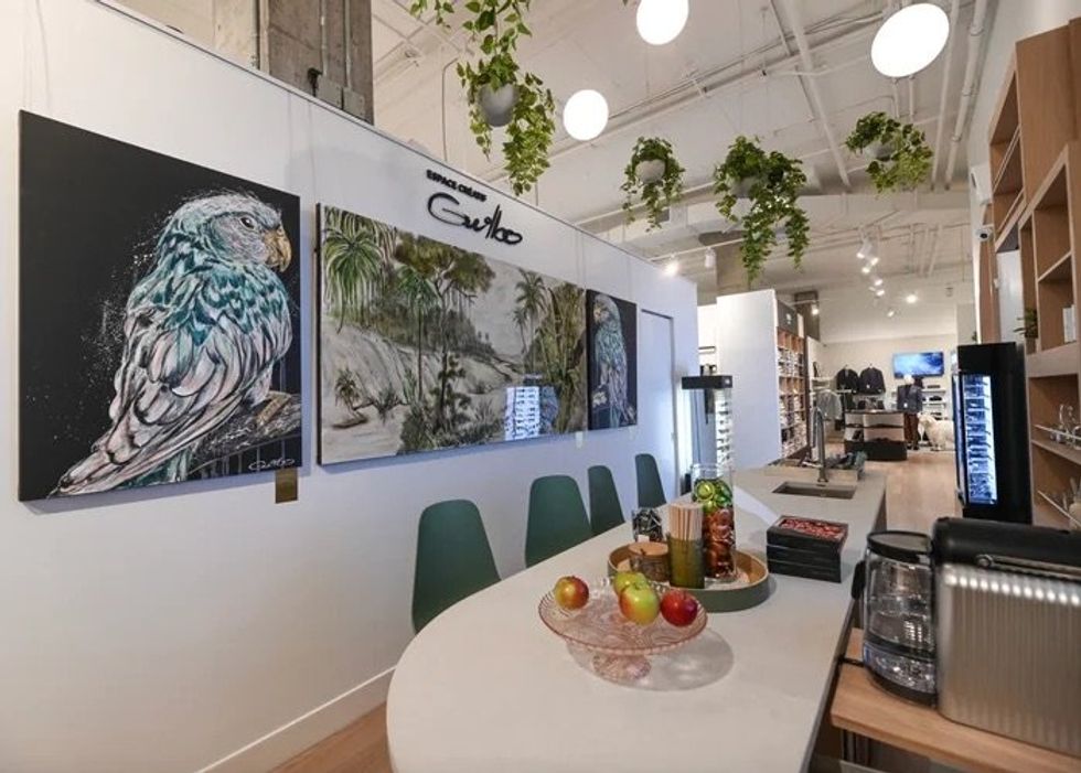 A sleek table with chairs and artwork behind it.