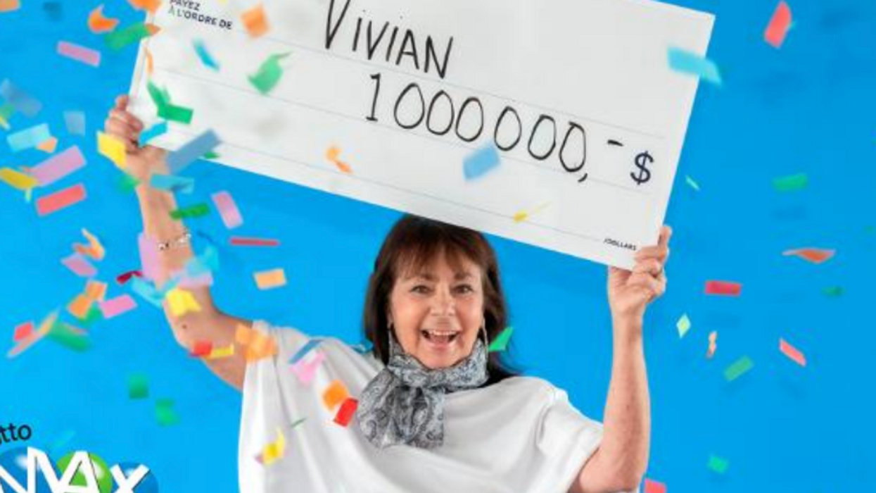 A smiling woman holds up a cheque for one million dollars.