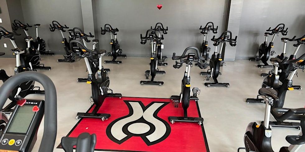 A spin room with multiple vacant spin bikes and a red carpet with the Centre \u00c9PIC de l'Institut de Cardiologie de Montr\u00e9al logo.