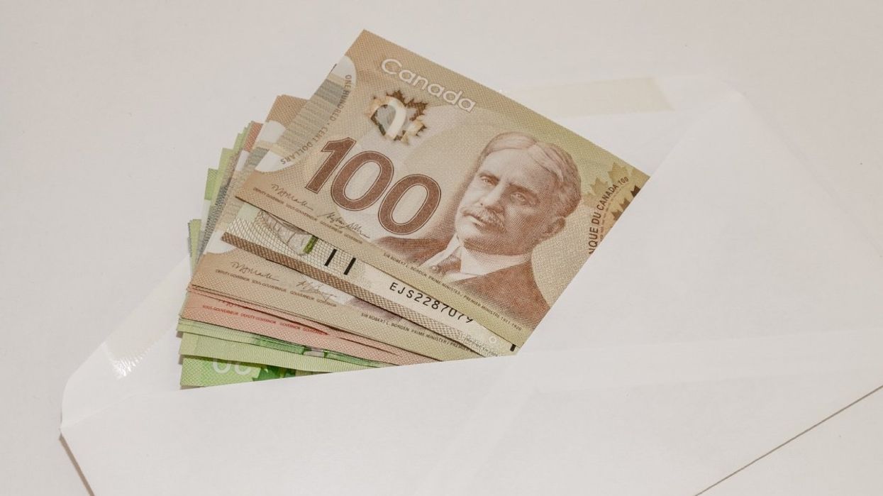 A stack of Canadian money in a white envelope.