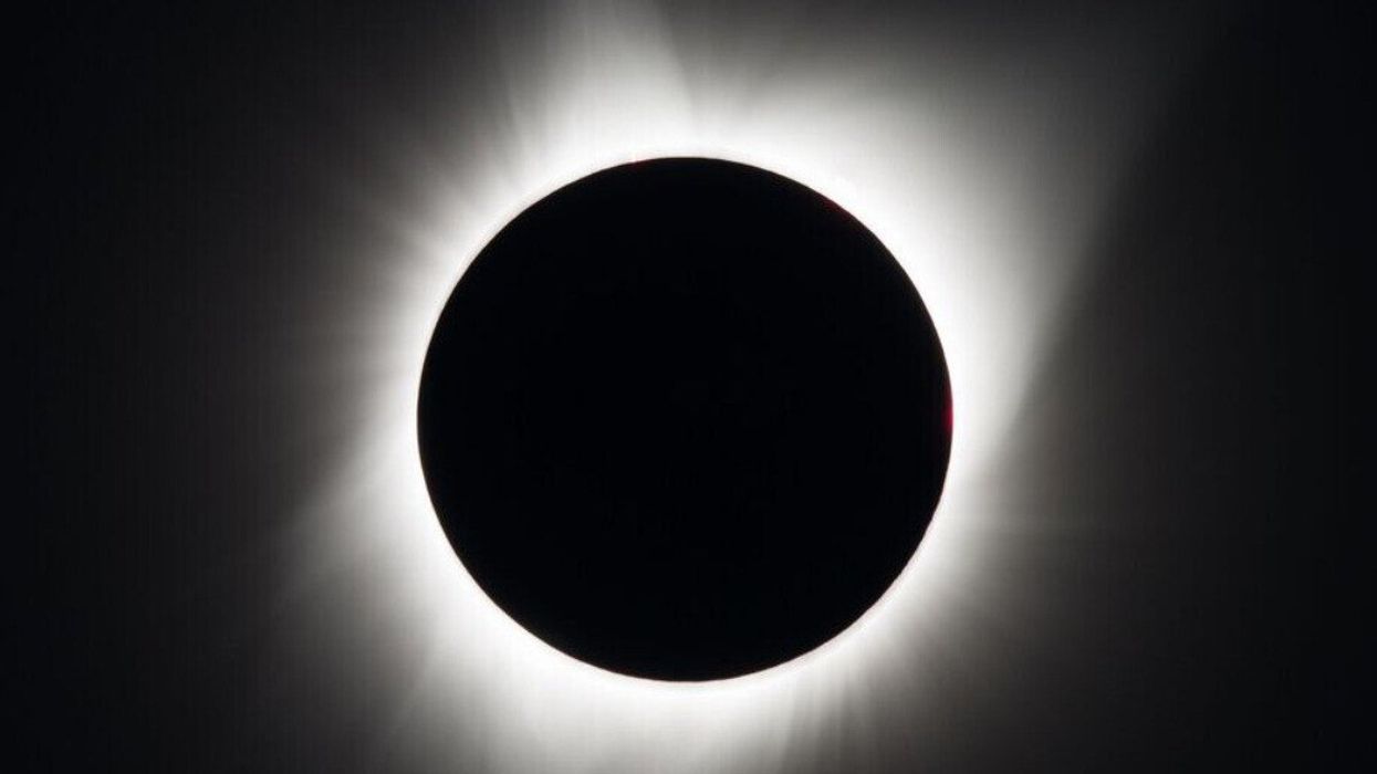 A stark black circle with a ring of light around it in a dark sky.