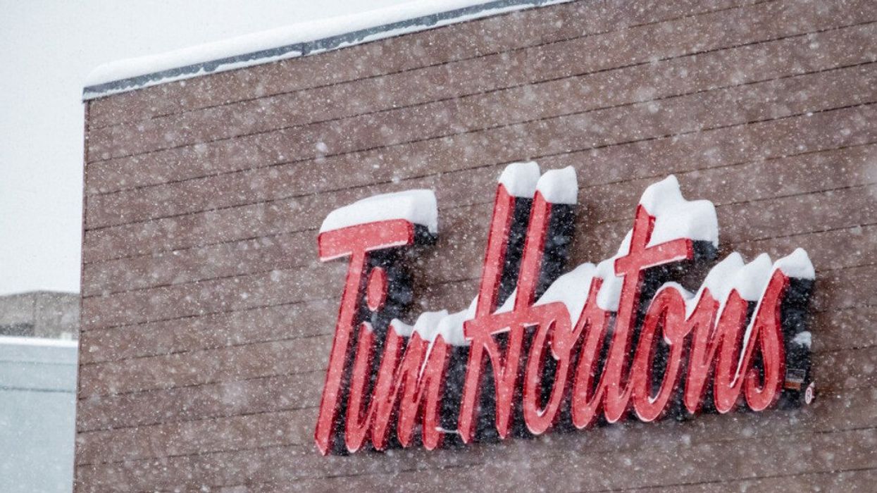 A Tim Hortons sign covered in snow during the winter.