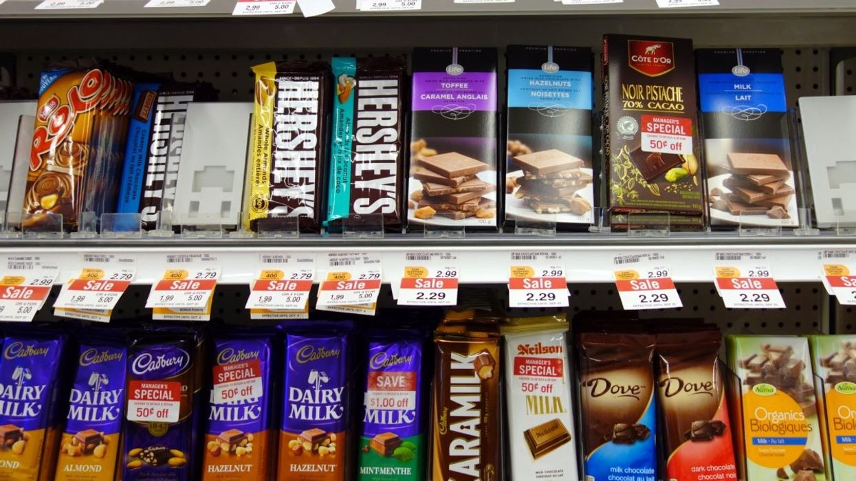 A variety of chocolate brands laid upright on a shelf at a grocery store in Canada.