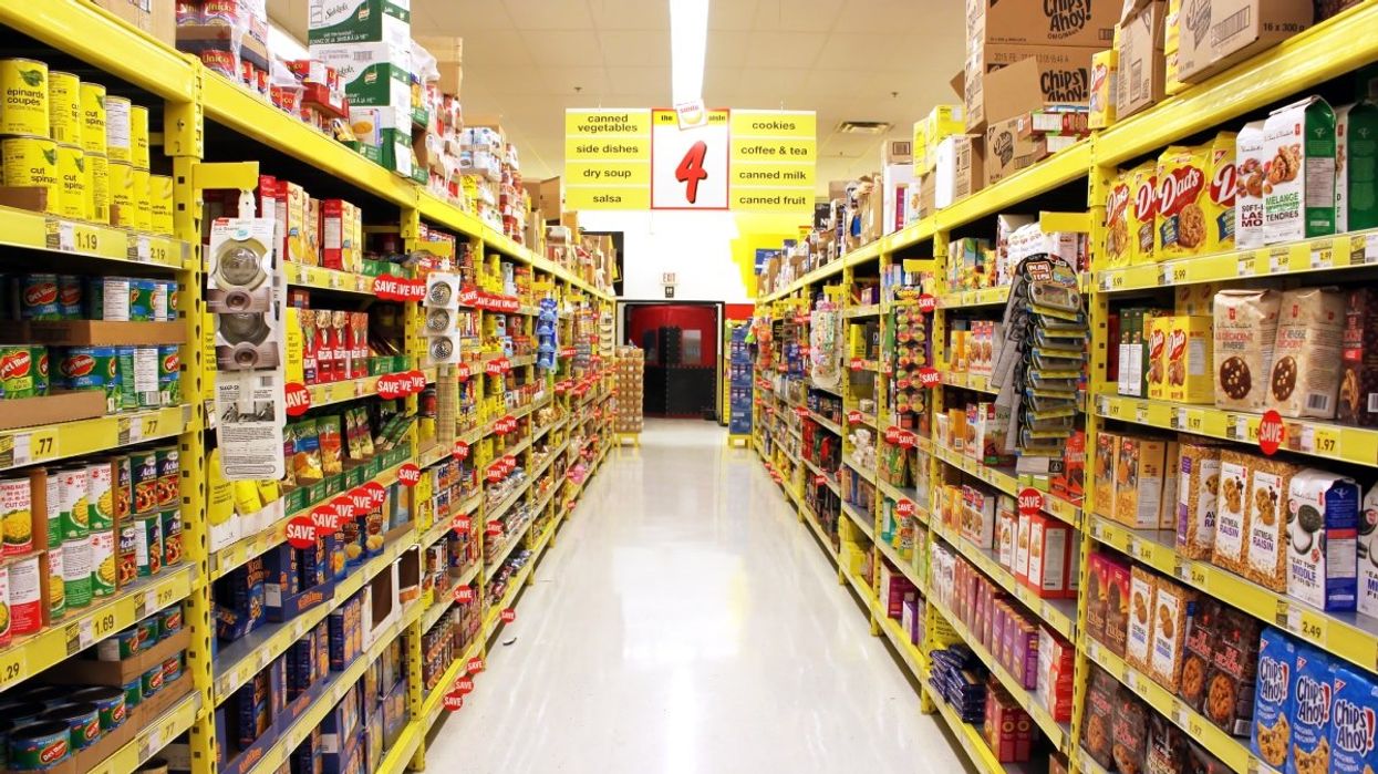 A view of an empty grocery store aisle in Canada with non-perishable items stacked on shelves.