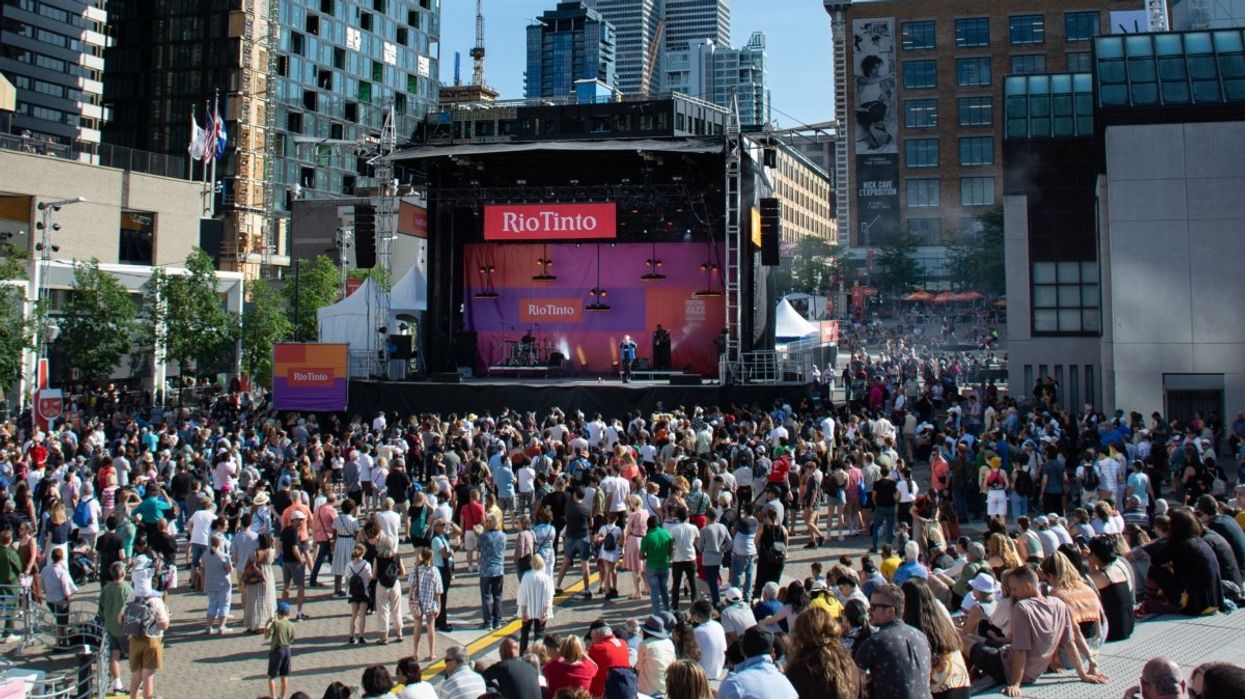 A view of the main stage at the Montreal International Jazz Festival at Quartiers des Spectacles with crowds of people watching.