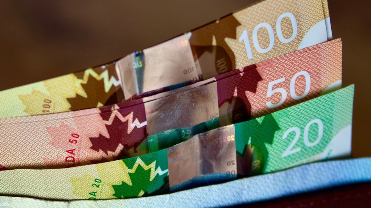 A wallet holding Canadian bank notes including $5, $20, $50, and $100 bills.