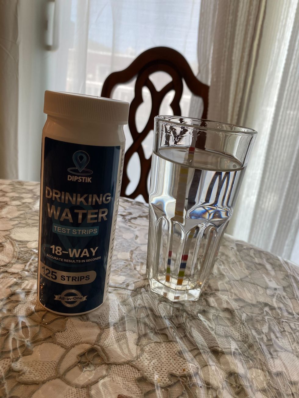A water test strip in a glass of water.