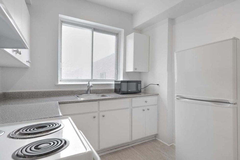 A white kitchen that includes a microwave, fridge, and stove.