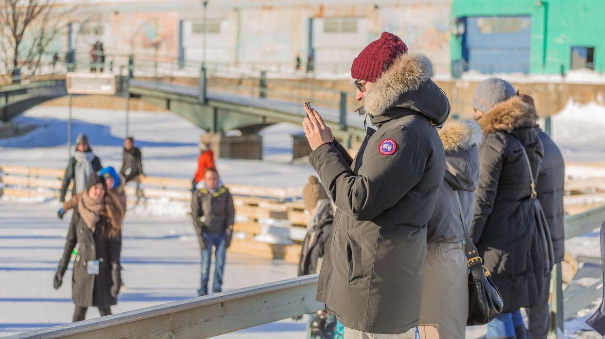 A woman taking a picture with her phone in a cold winter day in the Skating Rink in Old Port of Montreal. Quebec, Canada