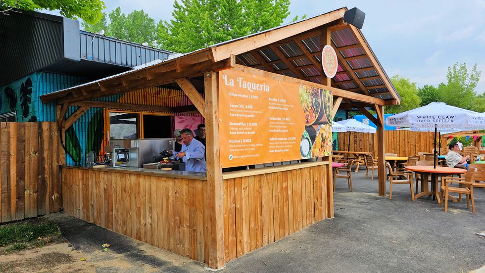 A wooden tacqueria with bright blue walls and green leaves now overlooks the beach with a seating area.