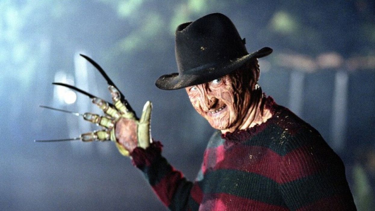Actor Robert Englund dressed as Freddy Krueger in a fedora, striped red and black sweater, and clawed glove.